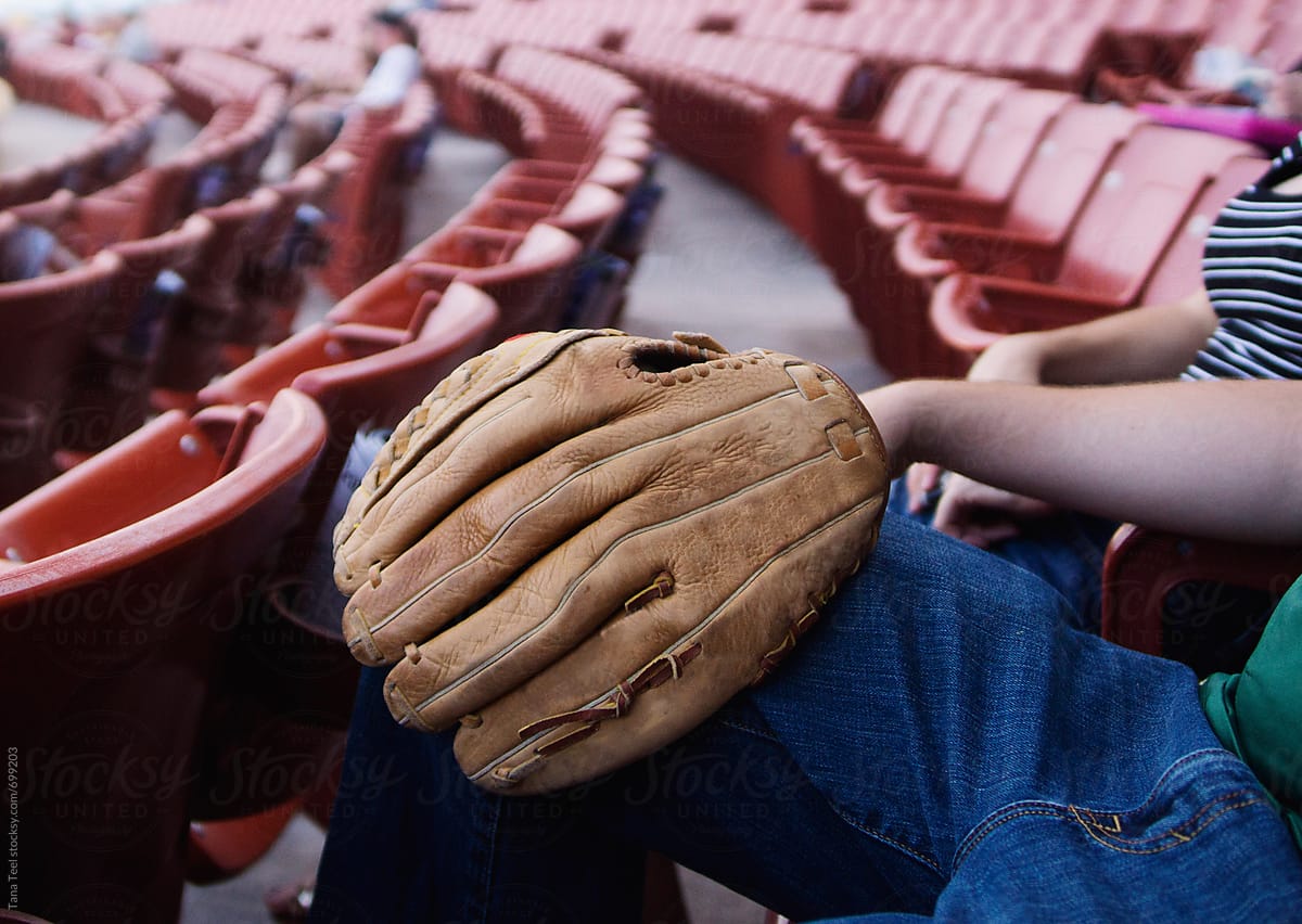 Man holds mitt in lap at baseball game