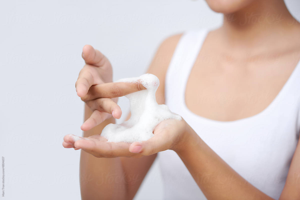 Close up of female hands holding, applying gentle foam facial cleanser
