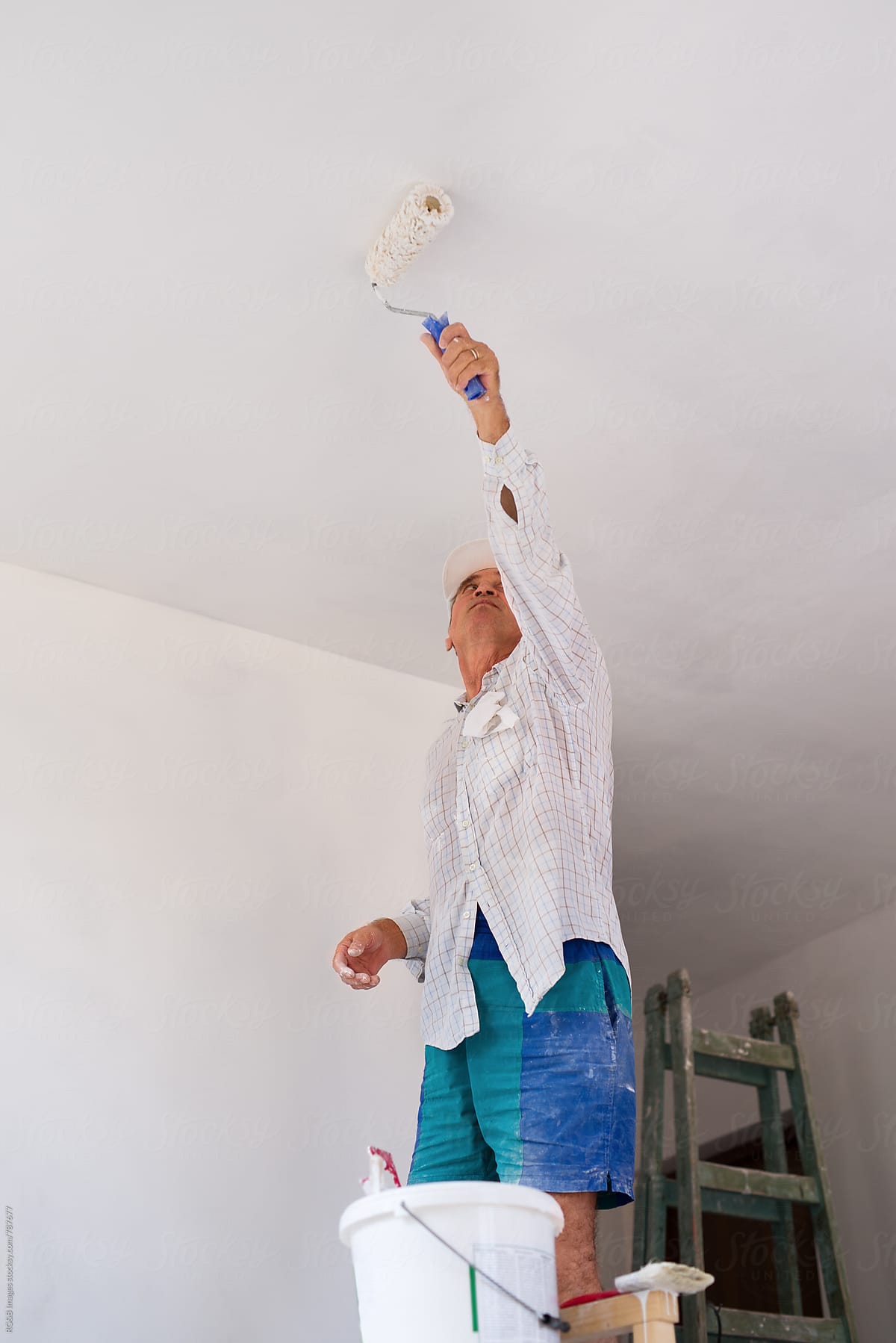 Craftsman painting the indoor walls white