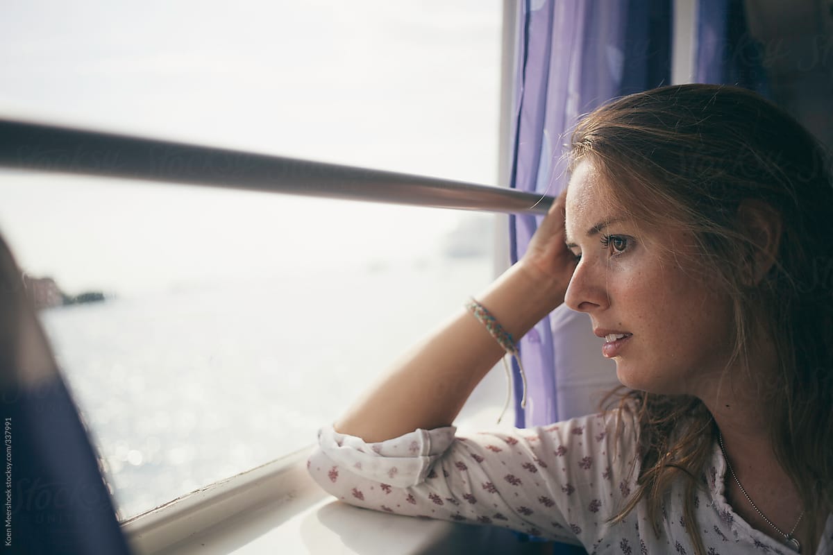 Woman on a boat daydreaming while looking out of the window.