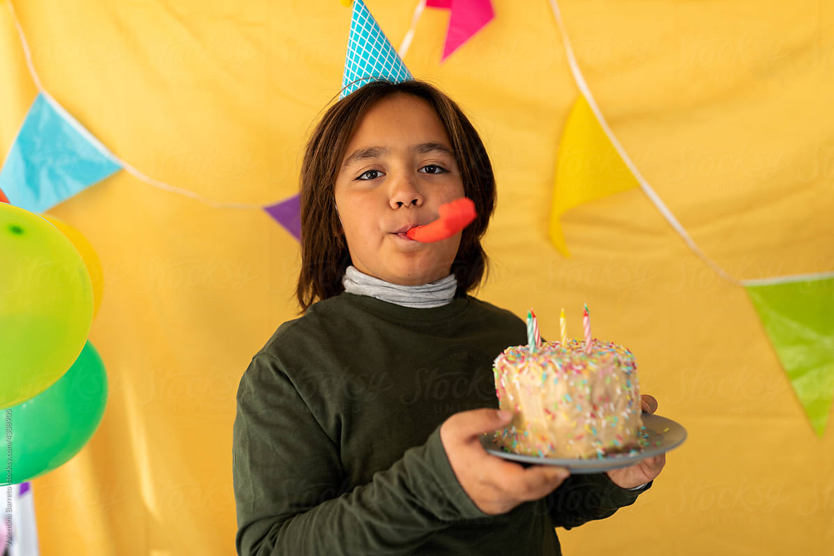 Boy with birthday cake and noisemaker