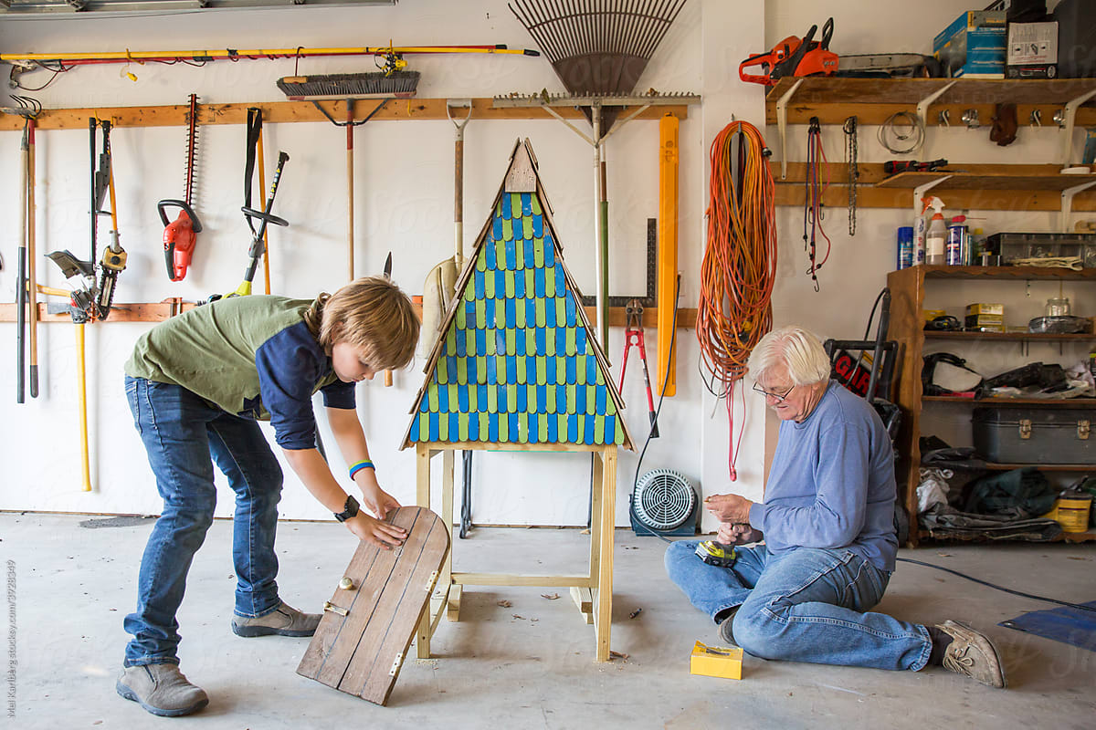 Grandfather and grandson building a small lawn decoration in a garage