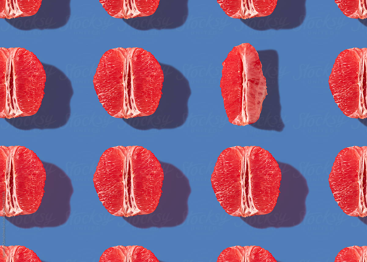Pattern of ripe grapefruit halves on a blue background. Creative layout for your ideas. Flat lay