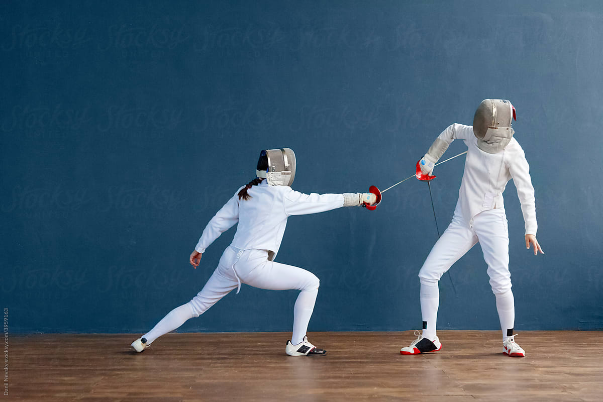 Female fencers practicing strikes in gym