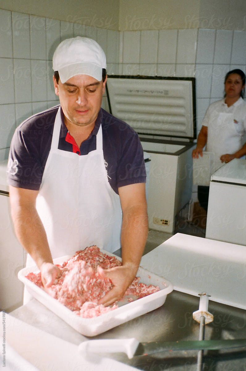 Butcher mixing meat with seasonings to make sausage at family butchery
