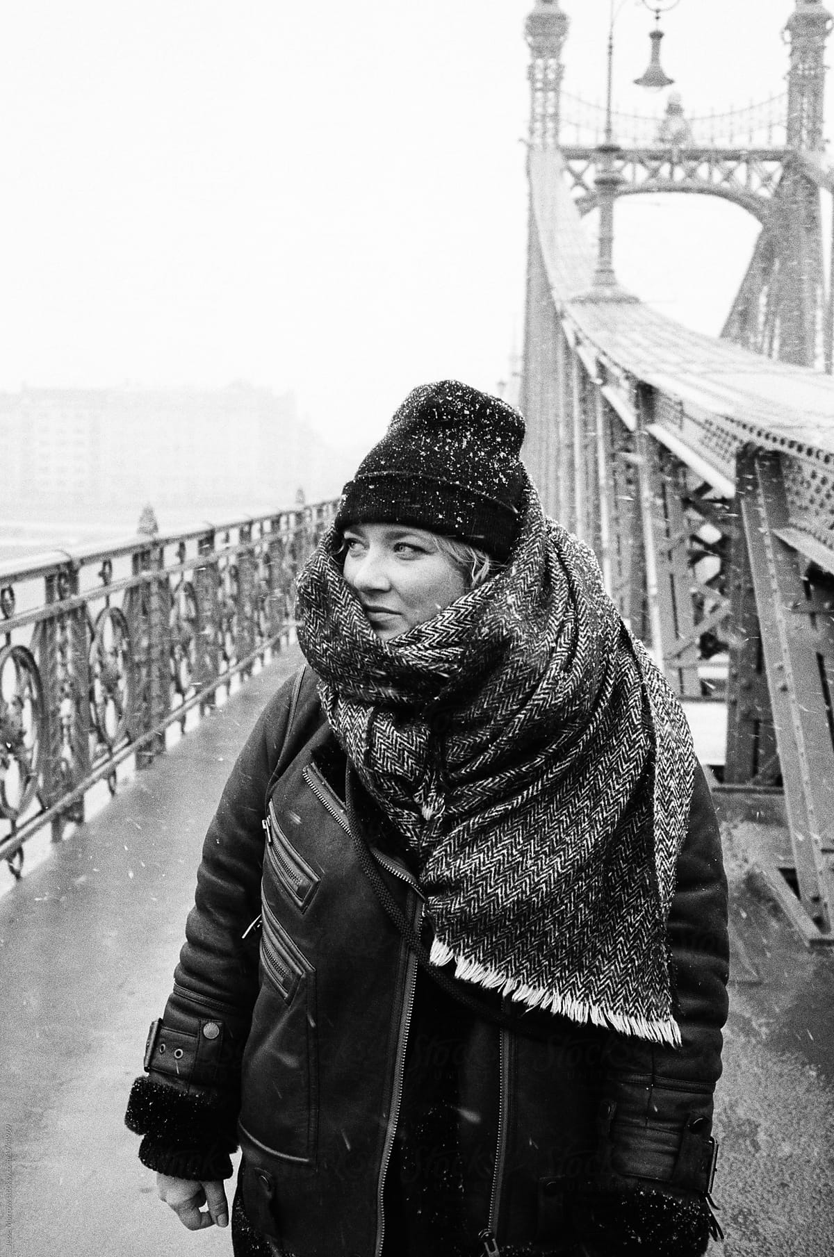 Young female standing in budapest hungary on bridge during snow storm black and white 35mm film