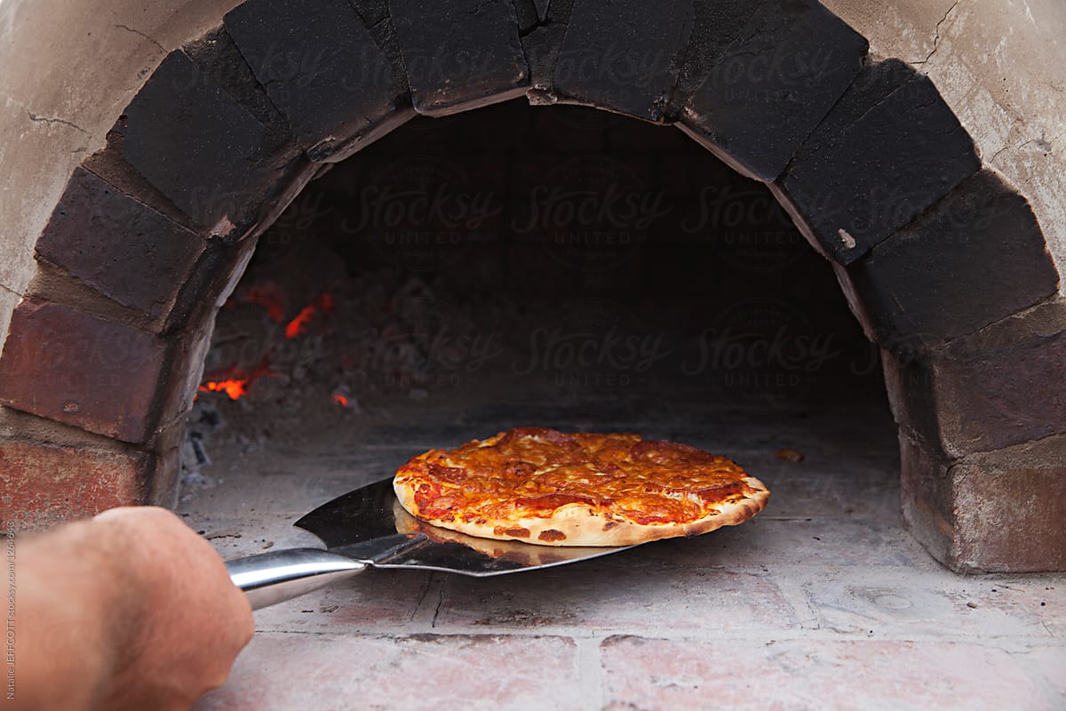 cooking home made pizza in wood fired oven