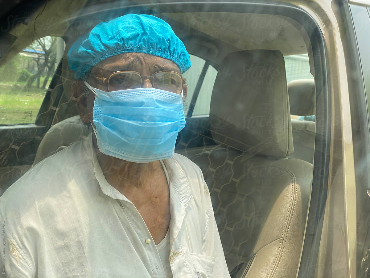 Senior Citizen Wearing mask and cap sitting in a car