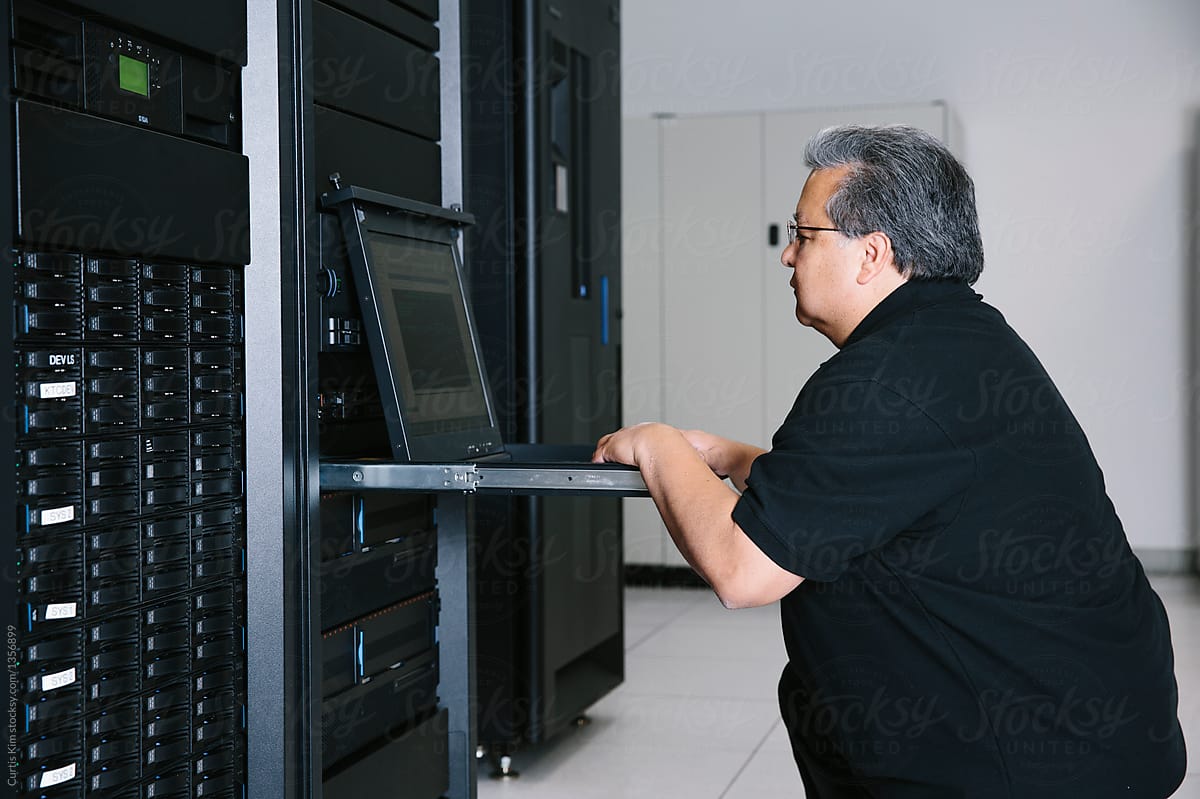 Computer expert working on datacenter servers on laptop