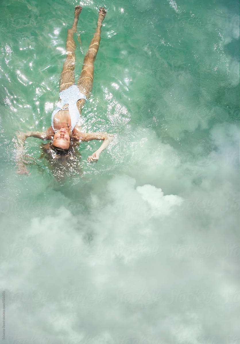 Woman on vacation floating in the ocean with clouds