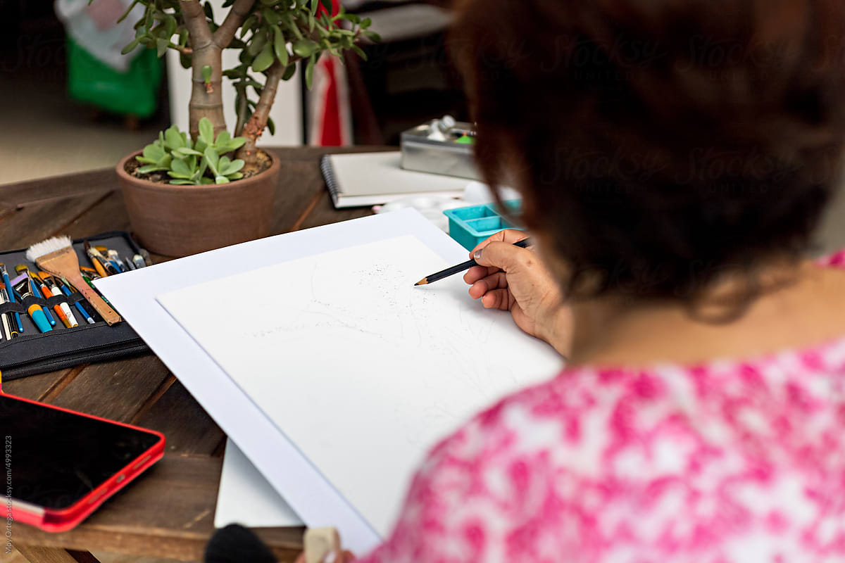 Third age woman using a pencil to create a sketch at home studio