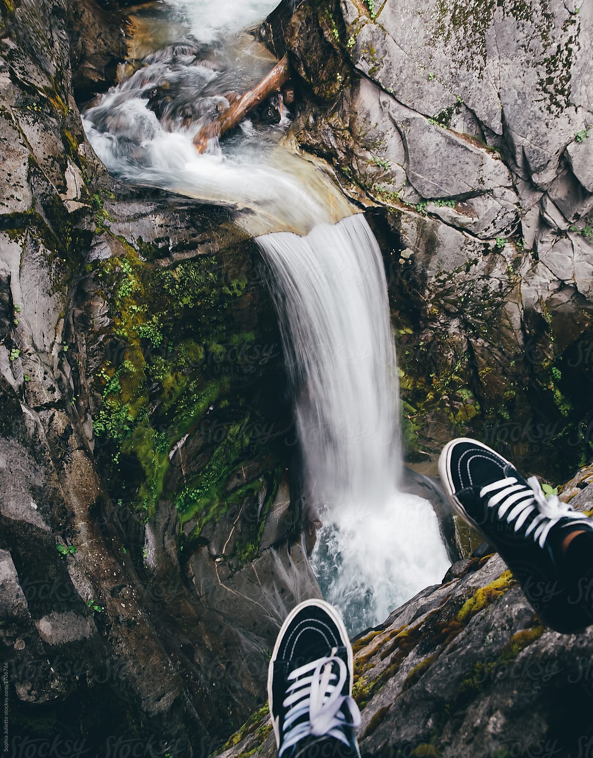 Feet Dangling Above the Daring Drop of a Vigorous Waterfall