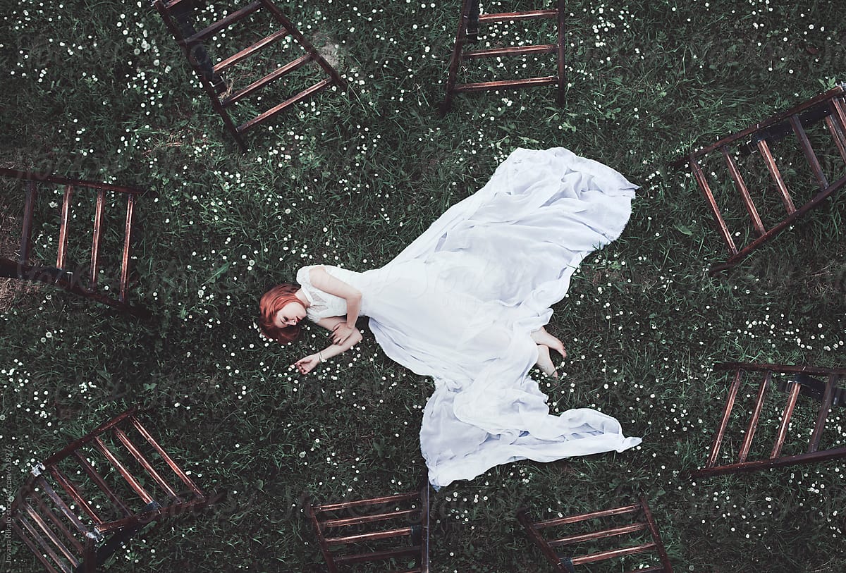 Young Woman Surrounded With Ladders Laying On Grass Del Colaborador De Stocksy Jovana Rikalo