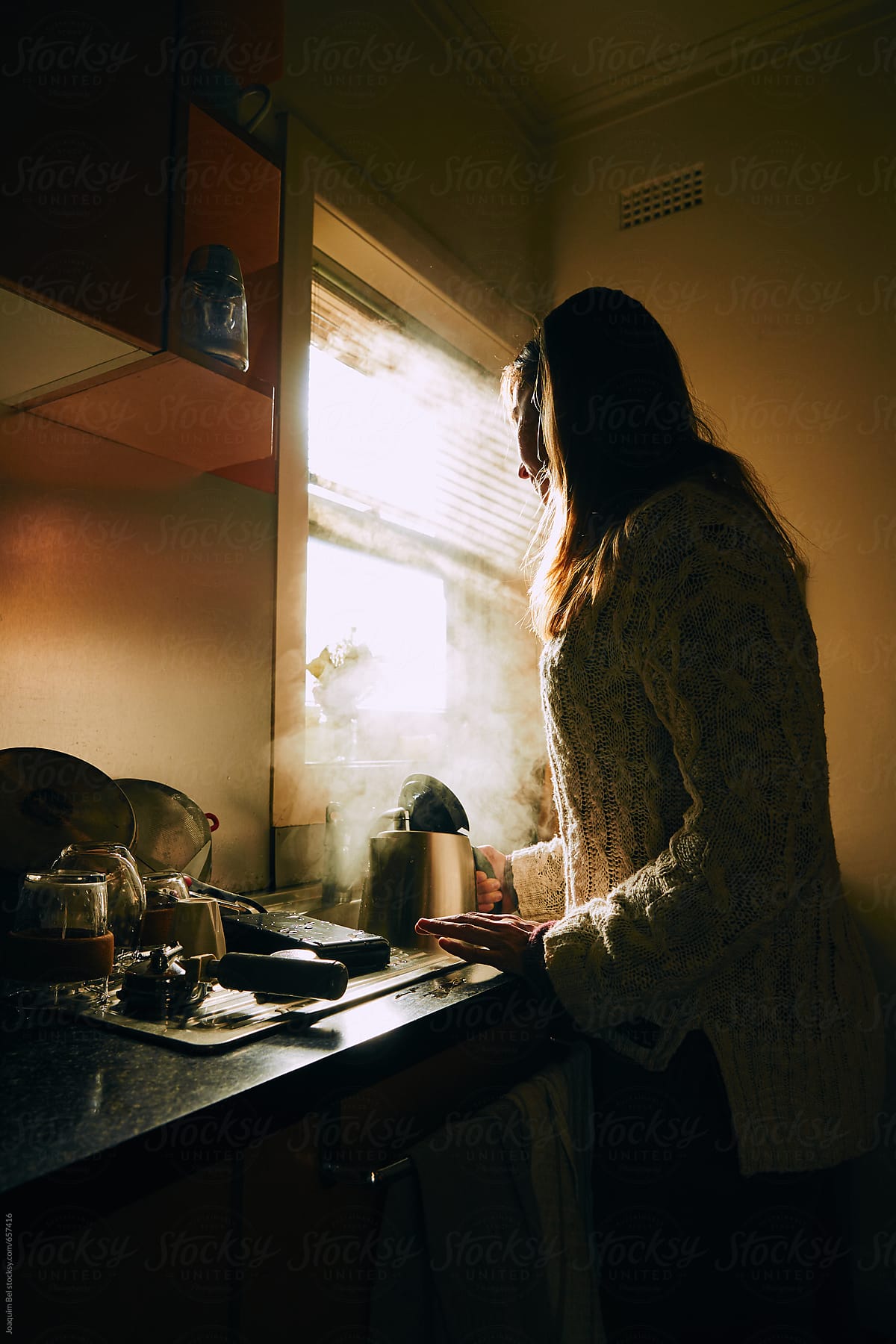Woman filling a kettle in a kitchen.