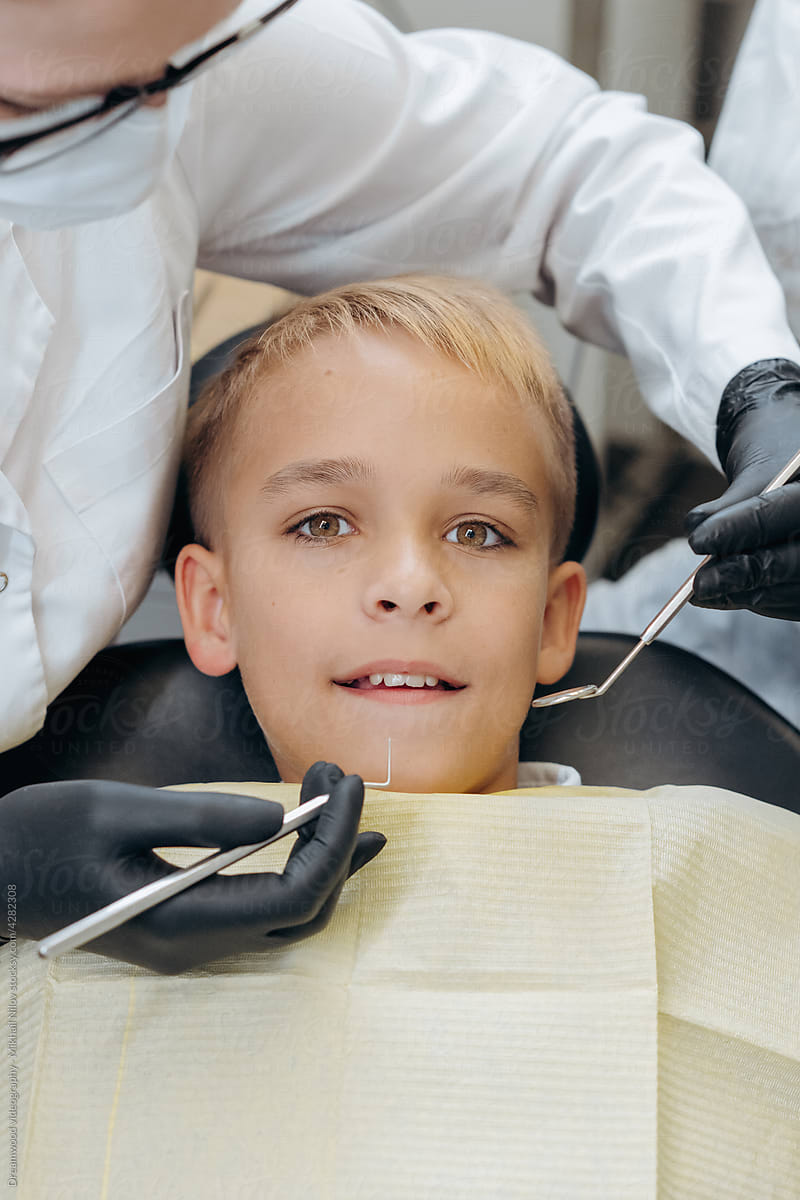 Dentists examine a young patient with instruments