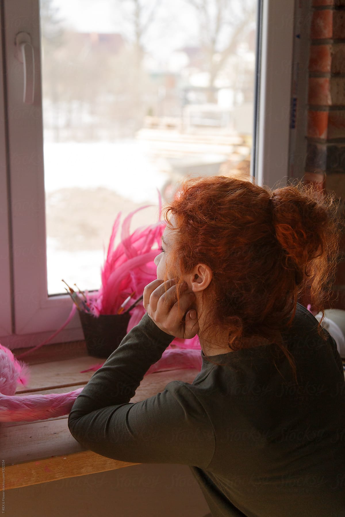 Pensive redhead woman looking at window