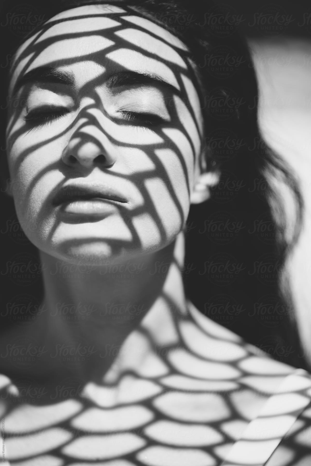 closeup of beautiful woman with a geometric patterned shadow on her face