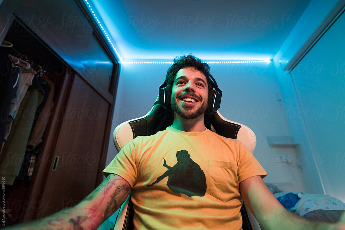 Gamer having fun playing in colour led bedroom