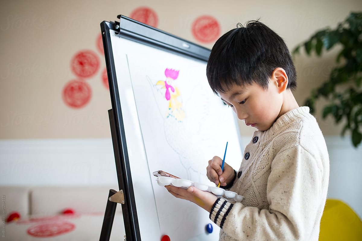 little asian boy drawing rooster indoor