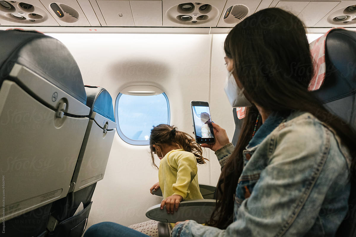 Mother taking photo of daughter in plane