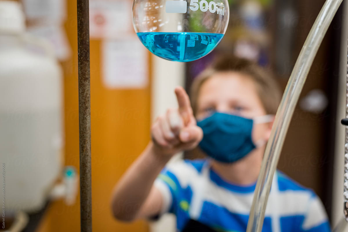 Boy with mask pointing at a chemical reaction