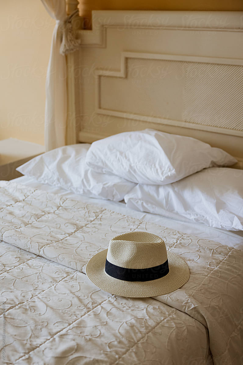 Elegantly placed fedora hat on a neatly made bed