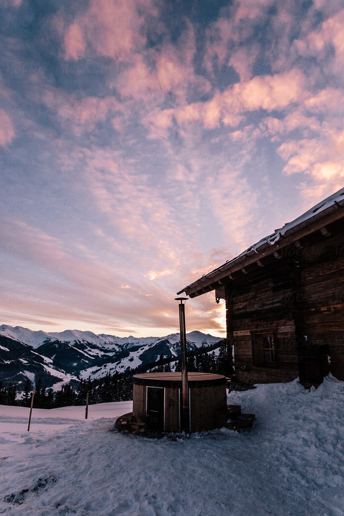 wooden alpine cabin with jacuzzi in alpine winter landscape