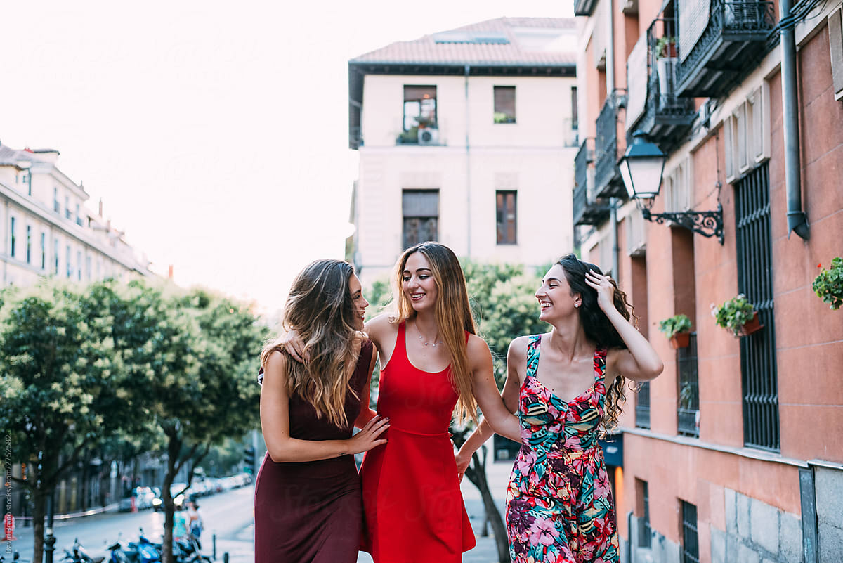 three women waking and laughing in a picturesque street in a sum