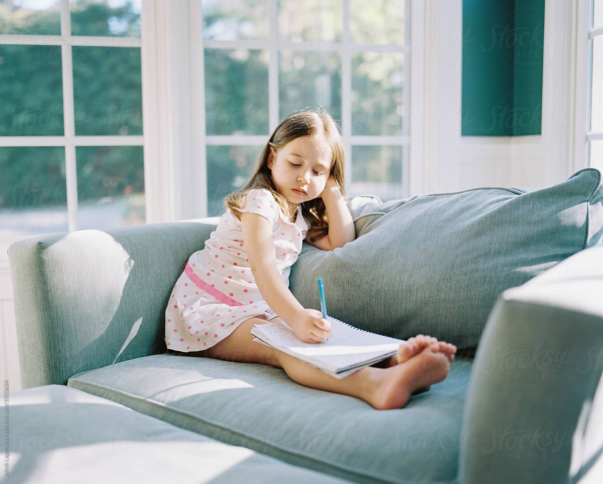 Cute Young Girl Sitting In A A Big Chair Practicing Her Writing Skills By Stocksy Contributor