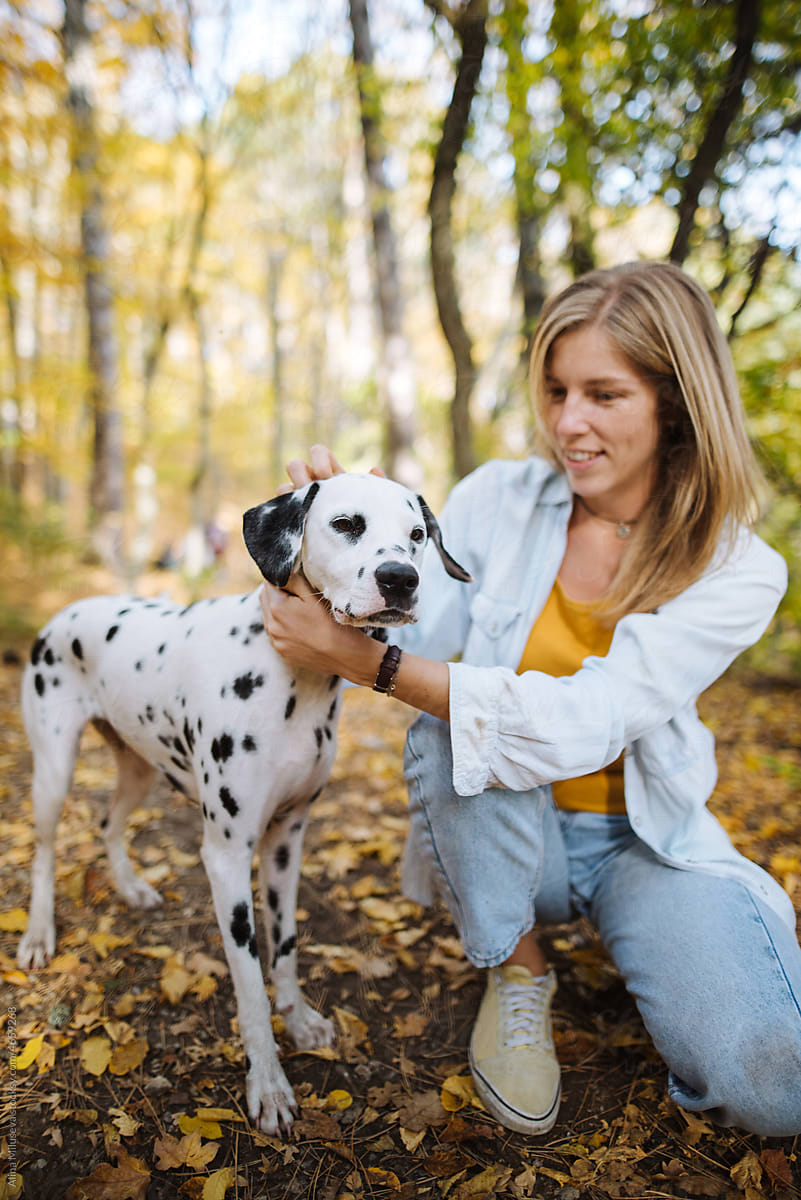 Smiling woman with her dog pet in autumn forest