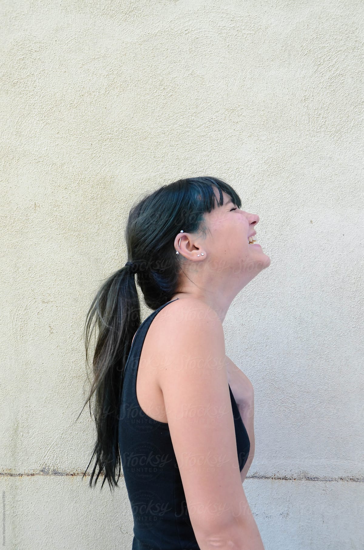 Side profile of young female laughing with turquoise hair