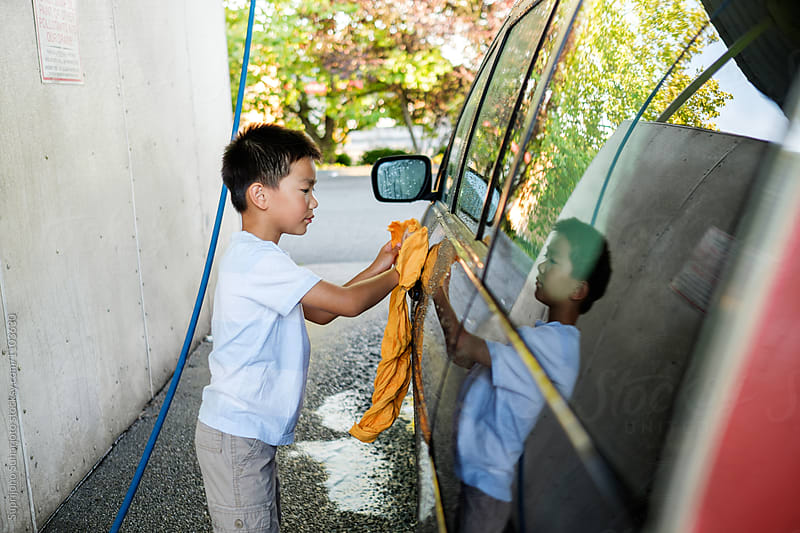 Asian kid washing a car at a car wash