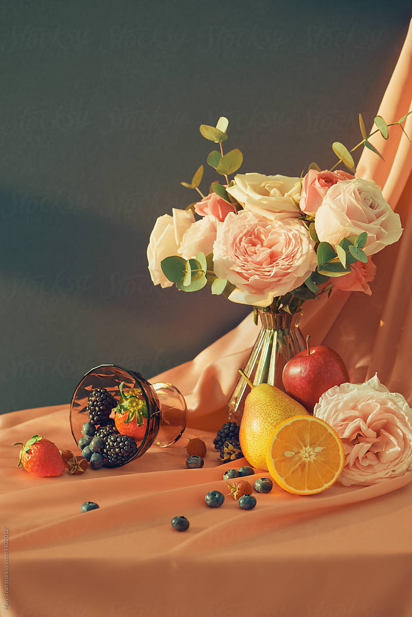 A bouquet of flowers in a vase with fruit