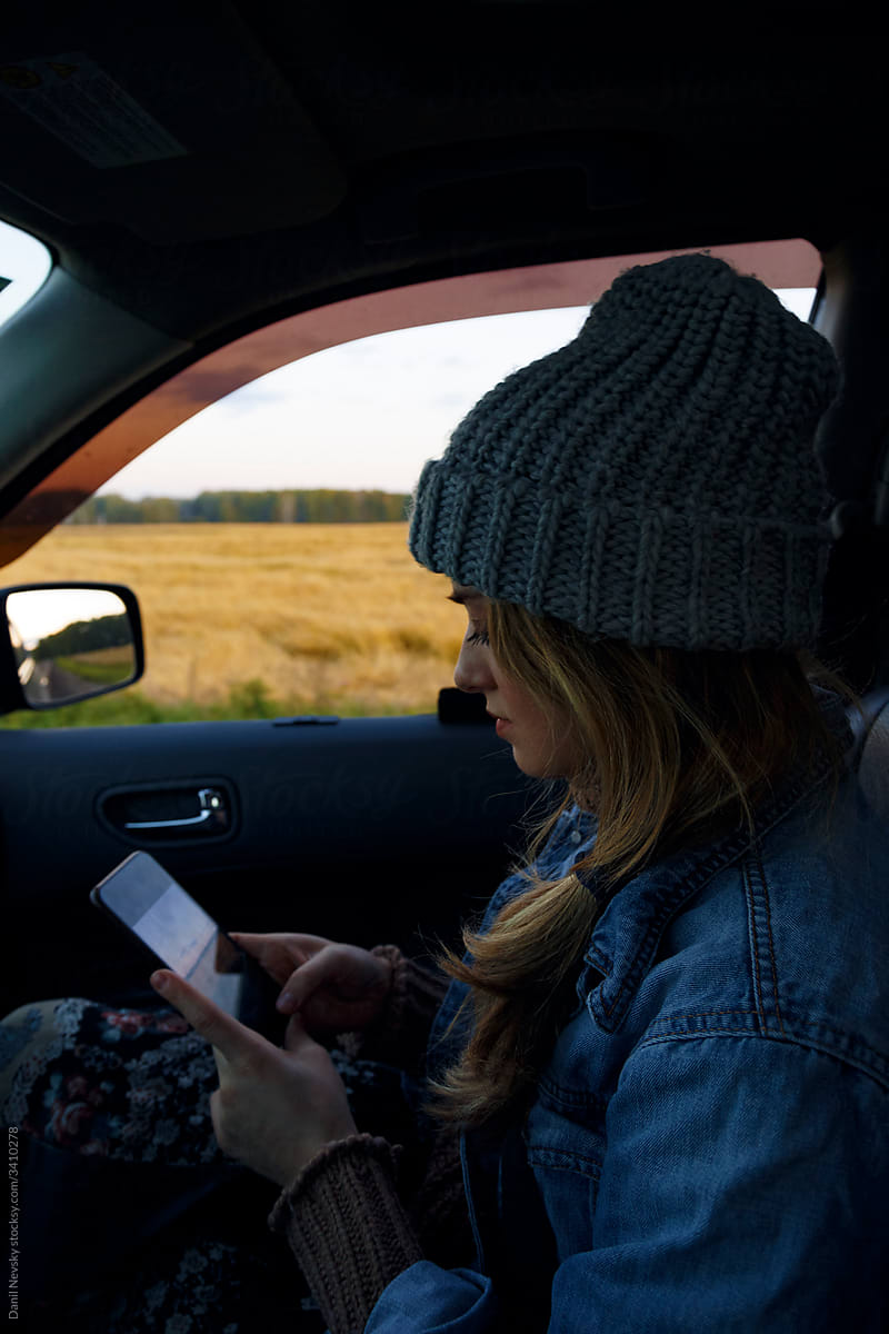 Young woman using smartphone in car in countryside