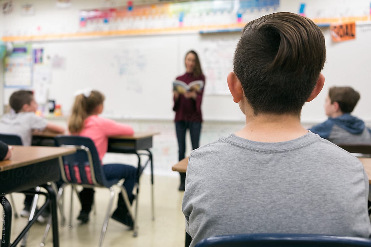 Classroom: Student Listens As Teacher Reads Out Loud To Class