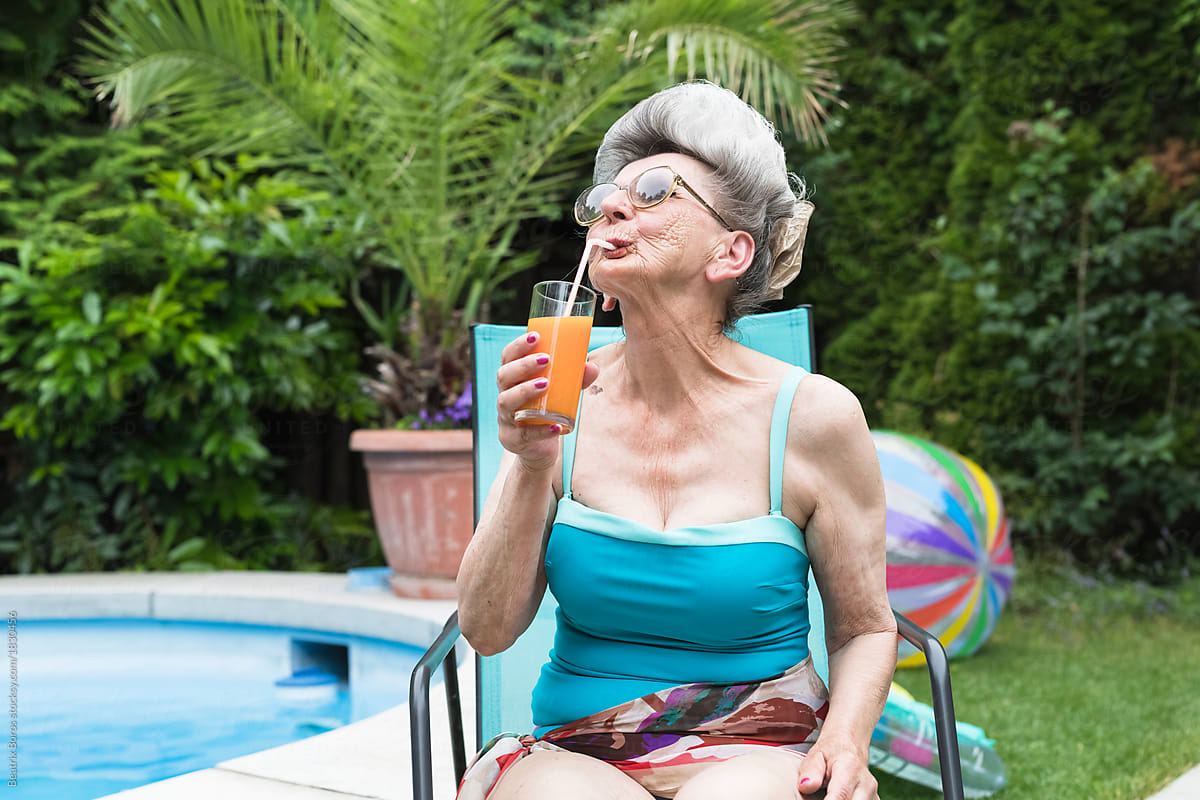 Cool progressive senior woman drinking a coktail in the garden