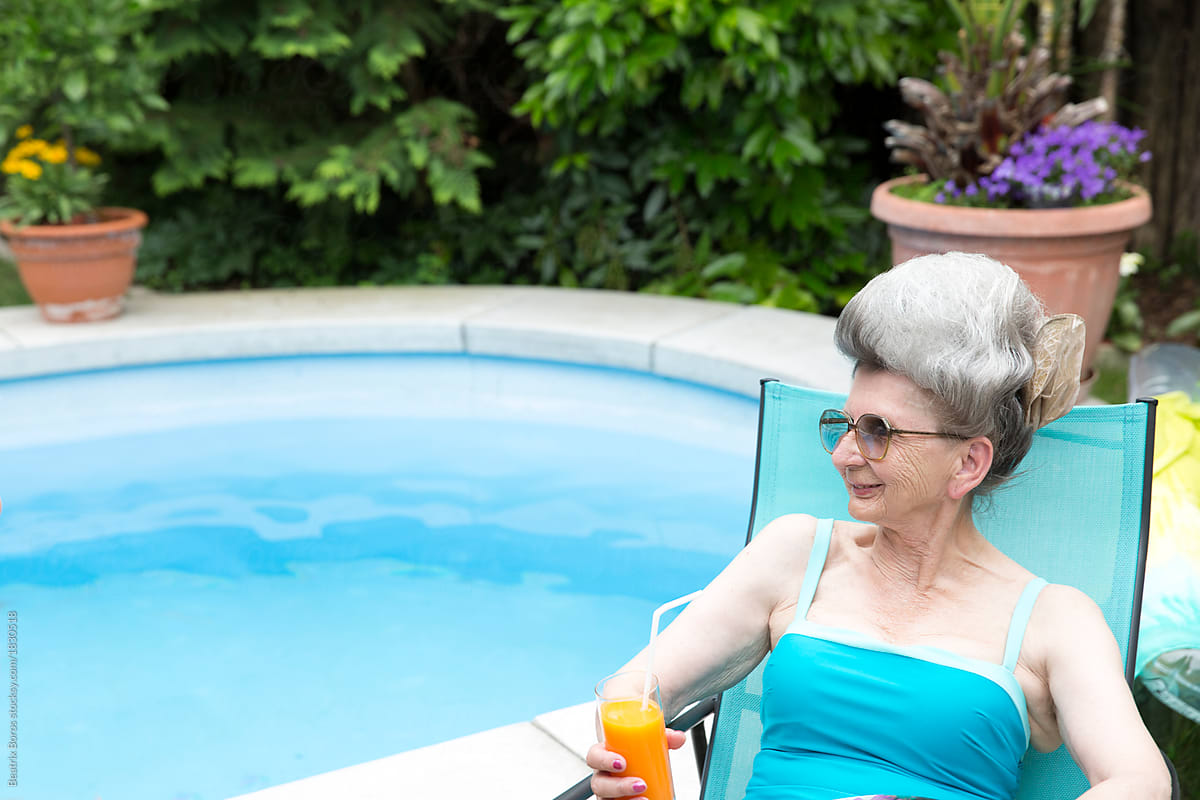 Woman Over 70 With Big White Hair Holding A Drink By The Pool Del Colaborador De Stocksy 0123