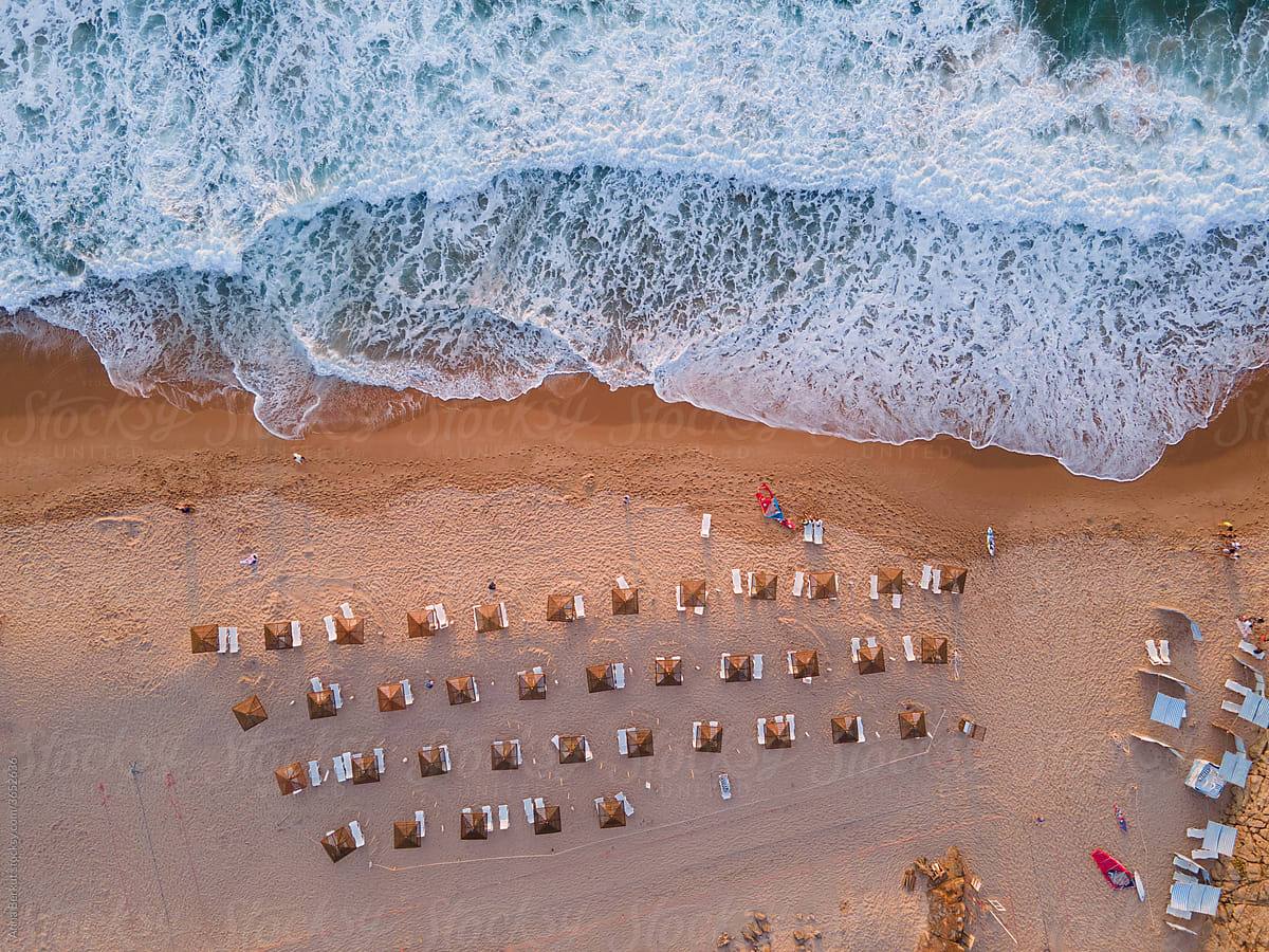 beach view from above, wave and umbrellas on sand