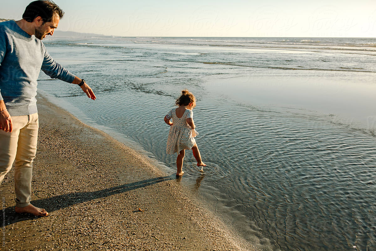 Little girl dips toe into ocean