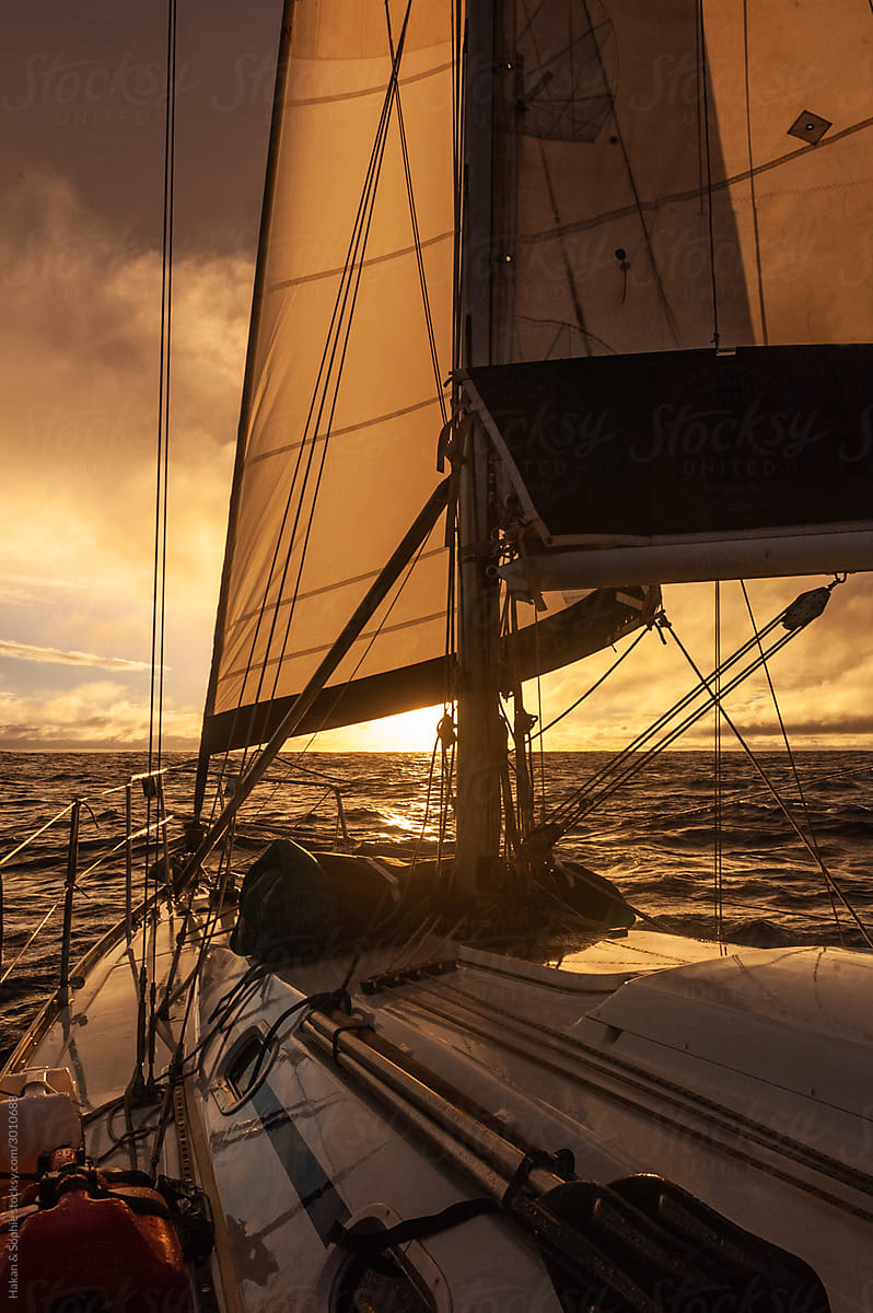 sailboat sailing towards sunset