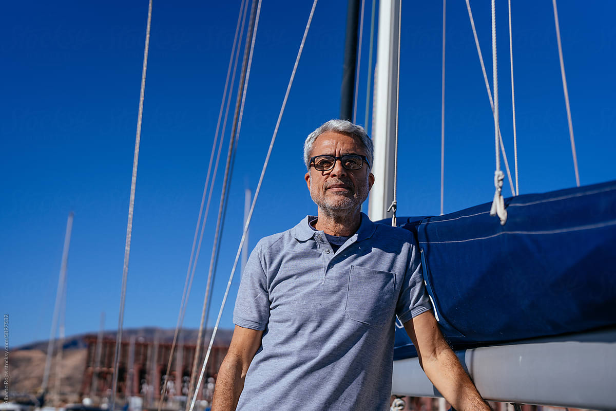Senior man standing on yacht against blue sky on sunny day