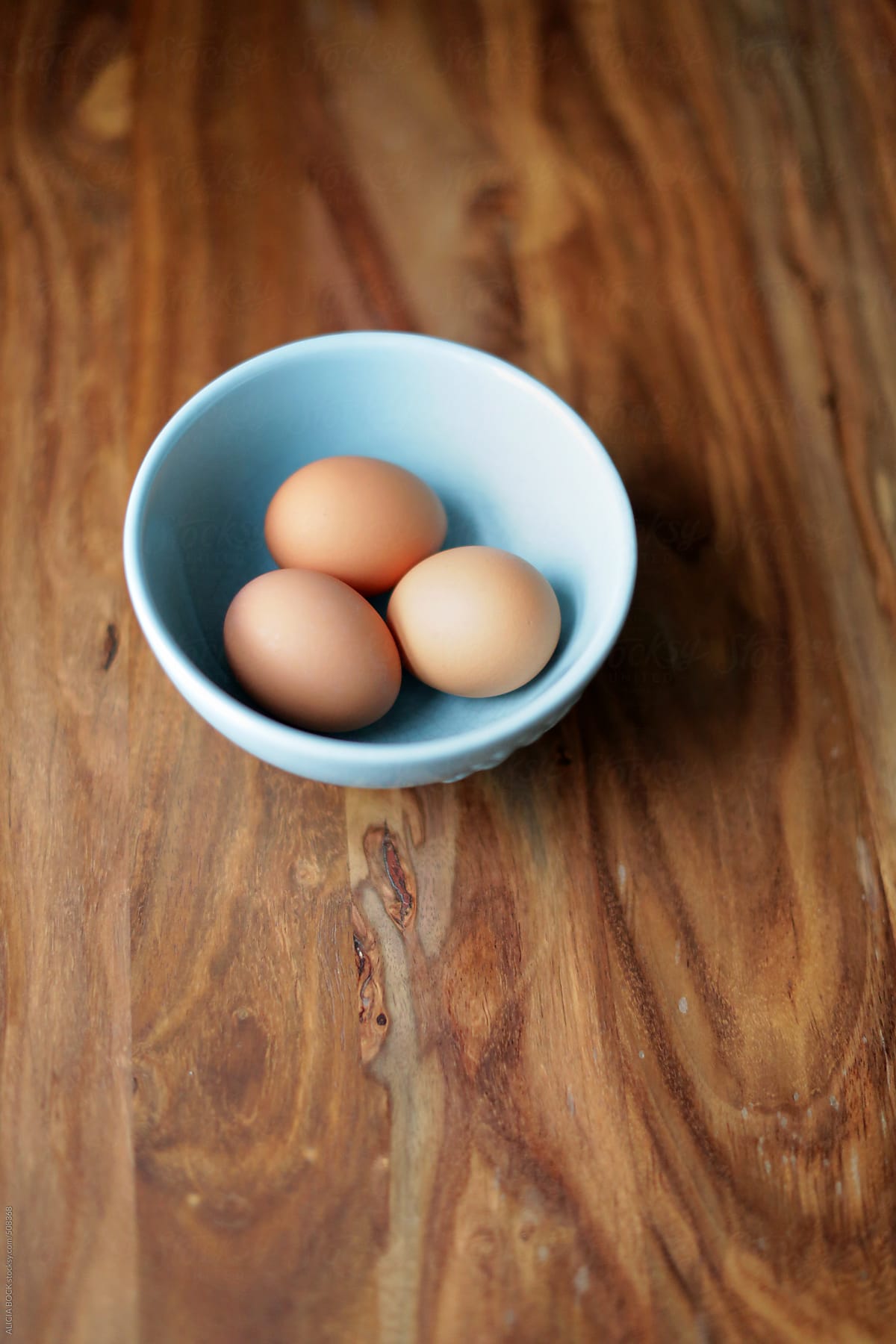 Three Brown Eggs In A Blue Bowl