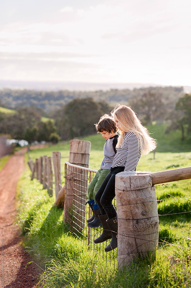 Children sitting on a farm fence