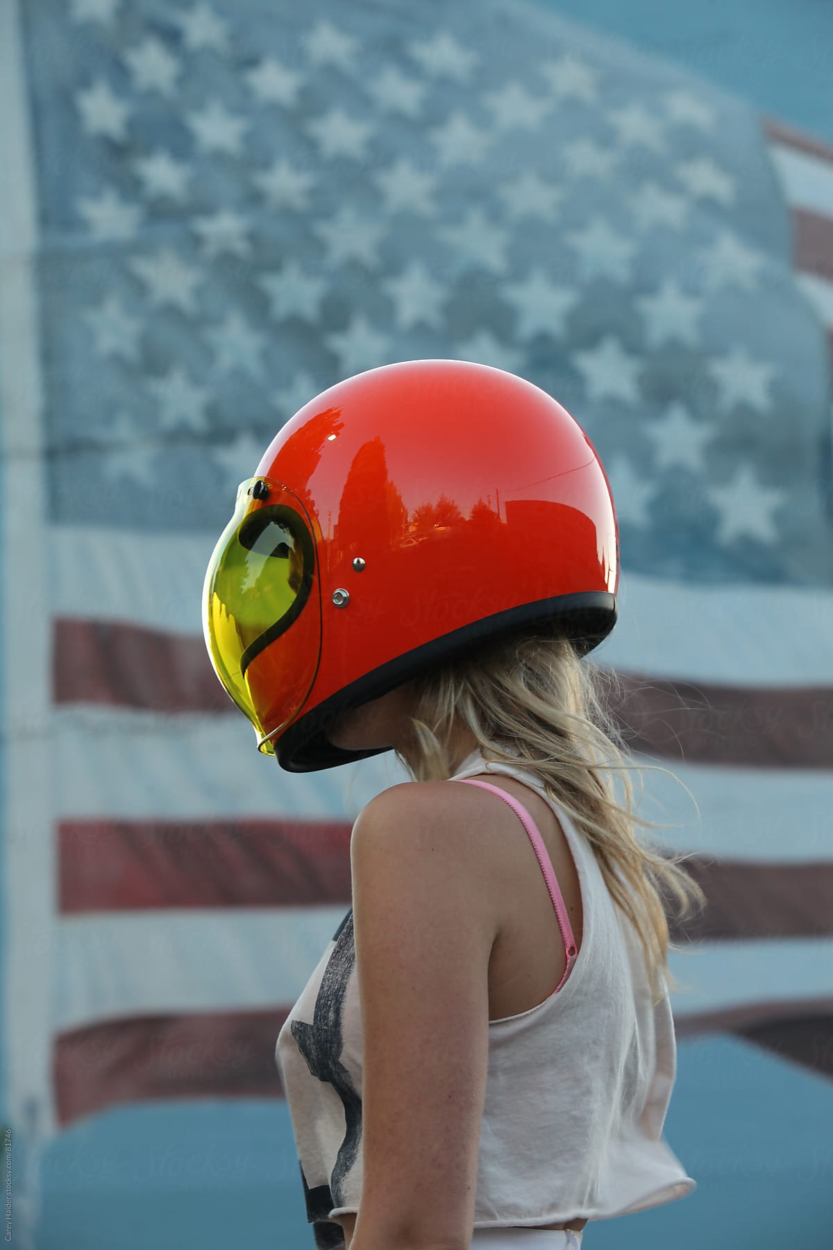 Americana Youthful Woman Wearing A Motorcycle Helmet Infront Of An American Flag