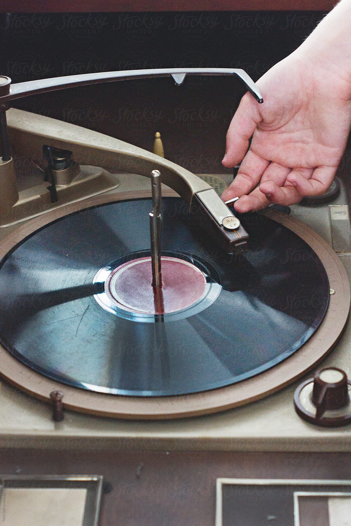 Teen places needle on a 78 vinyl record on turntable in vintage stereo