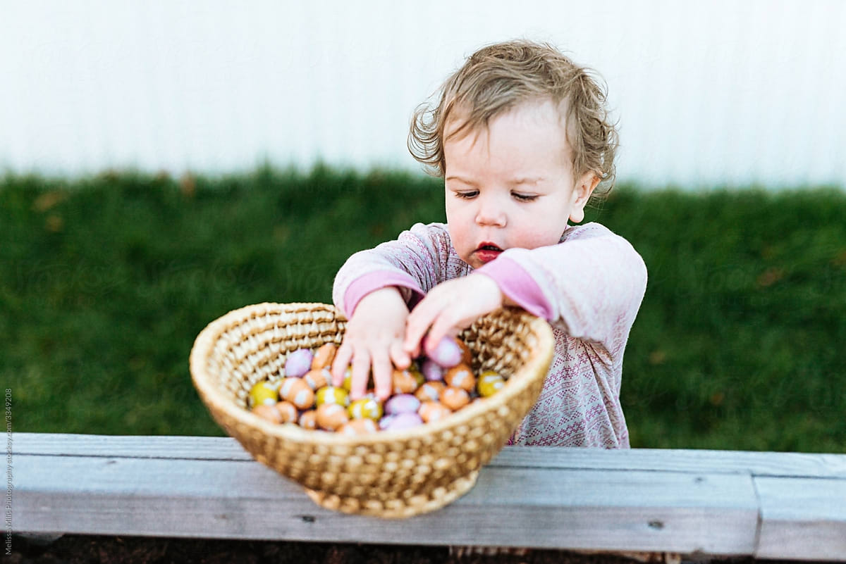 little girl in pajamas searching for eggs on easter day