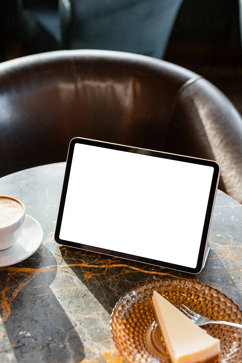 A tablet with white screen on a table in a cafe