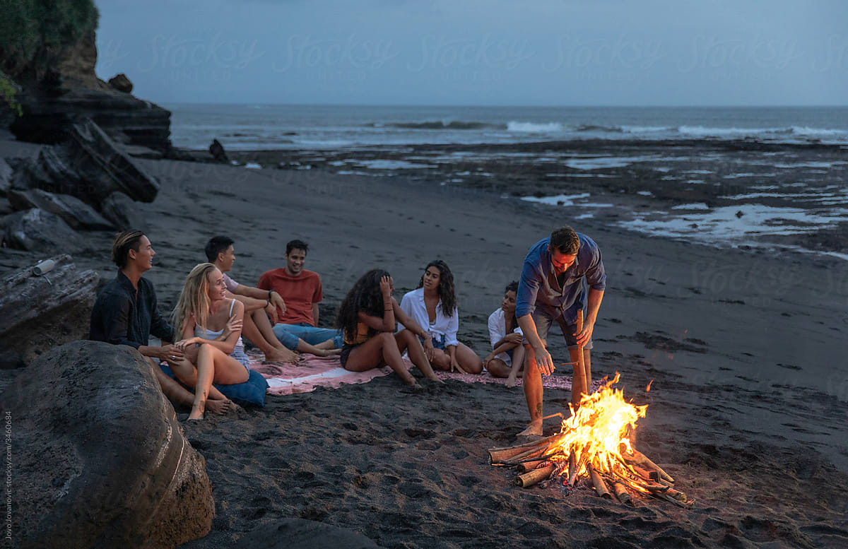 Group of friends hanging out at beach bonfire