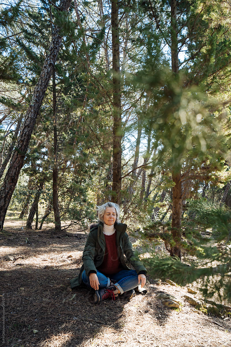 Mature woman meditating in forest
