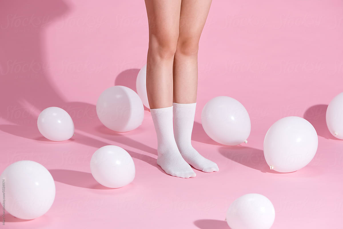 cropped shot of young woman in socks standing with balloons